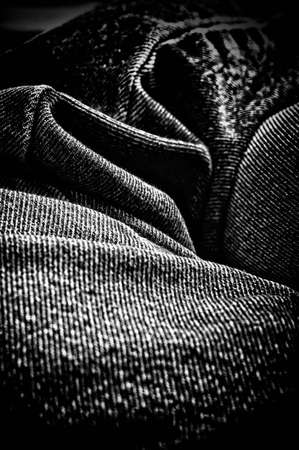 Looking along a rumpled piece of denim fabric making abstract design, finished artistically in high contrast black and white.の写真素材