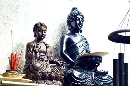 Two Buddha statues on shelf from different asian traditions with incense