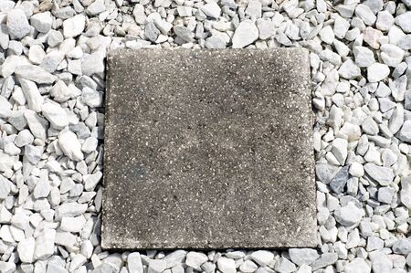 Looking down on square cement stepping stone surrounded by crushed white marble chips.の写真素材