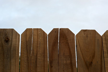 Looking up over the top of a wooden stockade fence towards the sky.