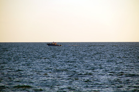 A boat is moving across the water on the gulf of mexico in bonita springs, florida as the sun sets.の写真素材