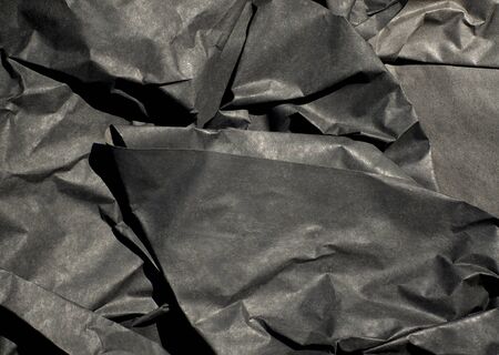 Close up of thick black semi gloss paper crumpled up with harsh shadows.の写真素材
