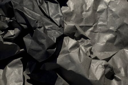 Close up of thick black semi gloss paper crumpled up with harsh shadows.の写真素材