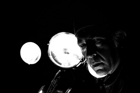 High contrast grainy image of male biker, back lit by headlights staring at viewer.の写真素材