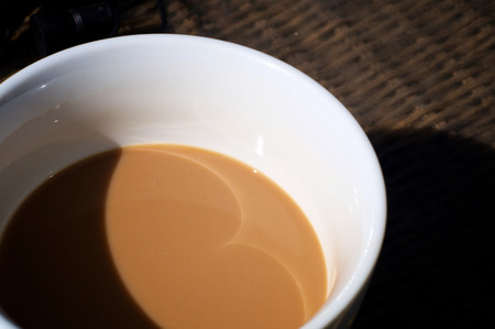 Looking down on a half full cup of coffee with cream in white cup.の写真素材