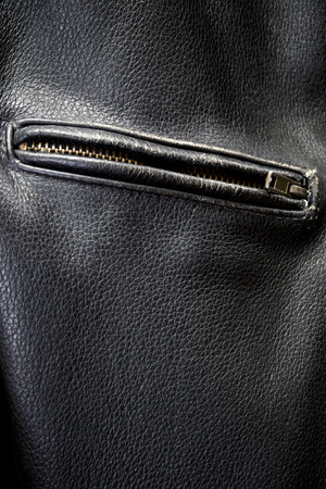 Close up of old black leather motorcycle jacket focusing on zippered pocket.の写真素材