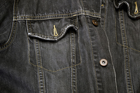 Detail of faded black denim cowboy jacket, focus on pocket.