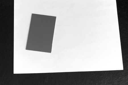 a small grey card on top of a white sheet of paper on top of a black textured surface.