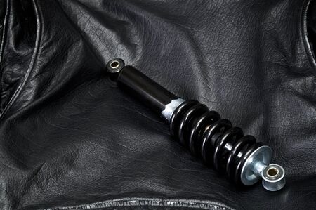 a brand new clean black and silver motorcycle shock absorber is laying across the back of an old...