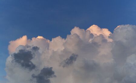 Large thick clouds against a blue sky and sunlight hitting the tops of the clouds.の写真素材