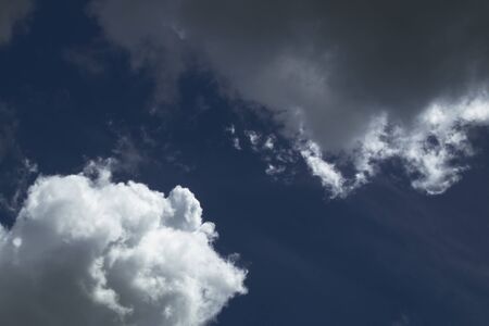 Blue sky cutting through at an angle dividing bright clouds from dark clouds.の写真素材