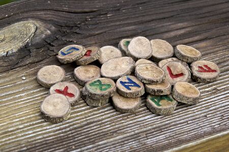 Collection of carved oak branch runes, known as the germanic futhark, on weathered wooden plank, used in magic and divinationの写真素材