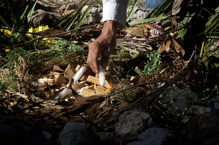 A mayan priest is lighting ceremonial fire with candles in a stone fire pit.の写真素材