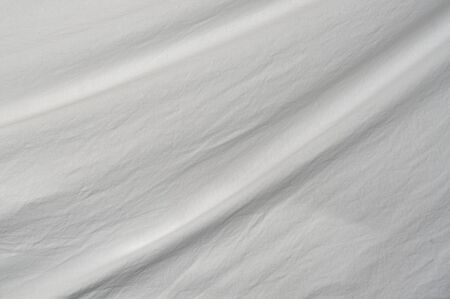 A gentle curve arcs through the frame from top right to bottom left of muslin cloth backdrop with small wrinkles.の写真素材