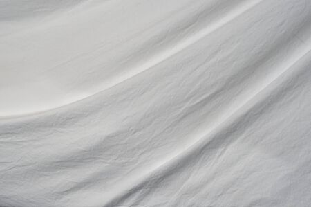 A soft curve arcs through the frame from top right to bottom left of muslin cloth backdrop with small wrinkles.の写真素材