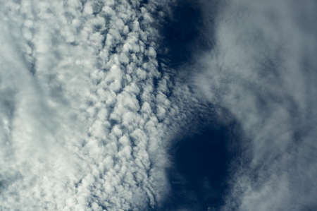 Looking up at a deep blue sky full of various types of cloud formations, fluffy and wispy.の写真素材