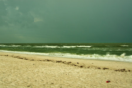 Thick storm clouds fill the sky over the gulf of Mexico in bonita springs, Florida, as waves crash on an empty beach.の写真素材