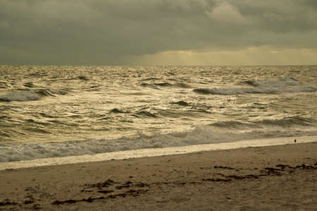 Thick storm clouds fill the sky over the gulf of Mexico in bonita springs, Florida, as waves crash on the beach.の写真素材