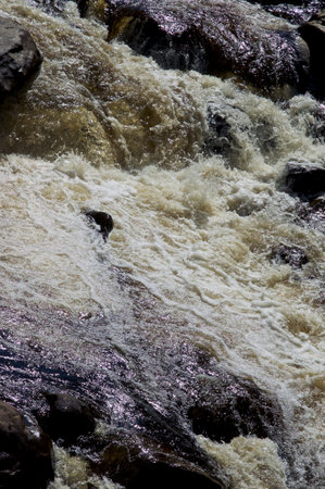 close up abstract view of rocky river in wilmington new york wilderness, with water rushing over large boulders creating foam or bubbles.の写真素材
