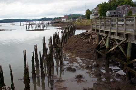 Wiscasset  Maine pier on overcast day in summer showing old houses, boats, rotting timber and oceanの写真素材