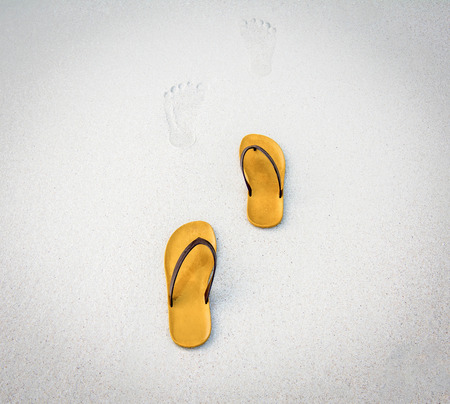 Footprints and brown shoes on White Sand Beach.の写真素材