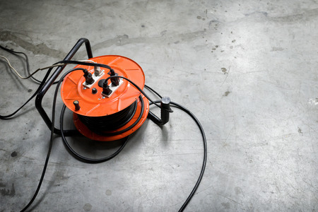 Cable reel Orange color Be plugged with Black Cable Wire Placed on the floor.の写真素材