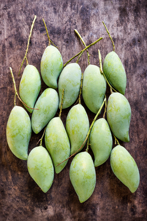 Fresh Green mangos in blue basket placed on the wooden floor.の写真素材