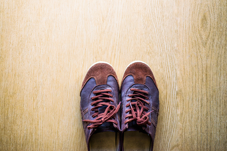 Old brown sneakers on a wooden floor top view.の写真素材