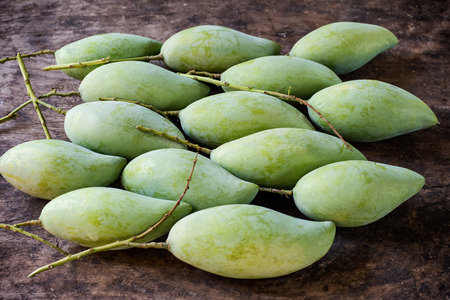 Fresh Green mangos in blue basket placed on the wooden floor.の写真素材
