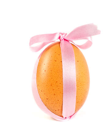 Easter egg, decorated a pink ribbon with a bow isolated on a white backgroundの写真素材