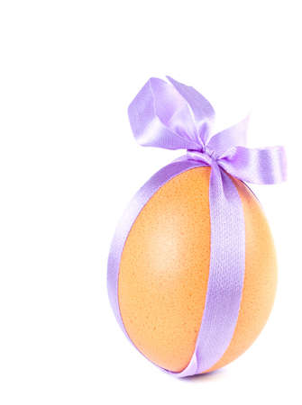 Easter egg, decorated a violet ribbon with a bow isolated on a white backgroundの写真素材