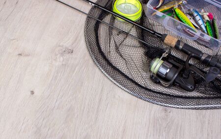 Fishing tackle - fishing spinning, fishnet, hooks and lures on wooden background.Top view.の写真素材