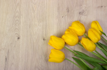 Yellow tulips on a wooden table, easter background, top view, flowers frameの写真素材