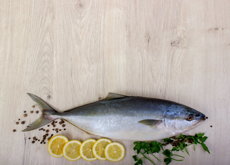 Fresh fish with lemon, parsley and spice on wooden cutting board isolated on whiteの写真素材
