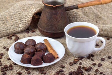 cup of coffee, saucer, truffle chocolates, cinnamon sticks on sackclothの写真素材
