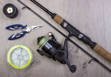 Fishing tackle - fishing spinning, hooks and lures on light wooden background.Top view.の写真素材