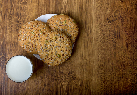 The composition of biscuits and a glass jar with milk. Cookies and milk white yogurt, on a white background with reflection. Tasty yellow brown cookies. Yogurt and oatmeal cookies.の写真素材