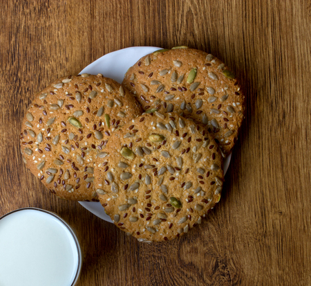 The composition of biscuits and a glass jar with milk. Cookies and milk white yogurt, on a white background with reflection. Tasty yellow brown cookies. Yogurt and oatmeal cookies.の写真素材