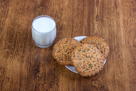 The composition of biscuits and a glass jar with milk. Cookies and milk white yogurt, on a white background with reflection. Tasty yellow brown cookies. Yogurt and oatmeal cookies.の写真素材