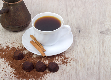 cup of coffee, saucer, truffle chocolates, cinnamon sticks, on wooden backgroundの写真素材
