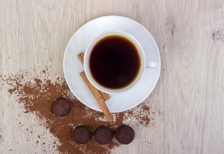 cup of coffee, saucer, truffle chocolates, cinnamon sticks, on wooden backgroundの写真素材