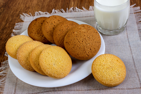 food, junk-food, culinary, baking and eating concept - close up oatmeal cookies and milk glass on a napkinの写真素材