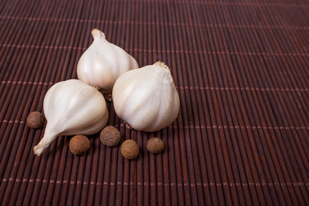 head of garlic and peppercorns on wooden backgroundの写真素材