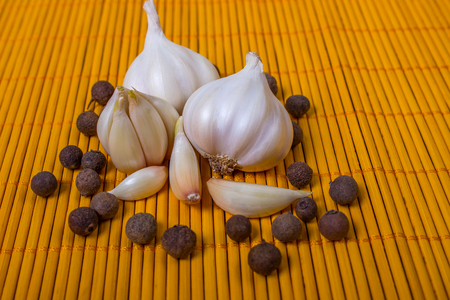 head of garlic and peppercorns on wooden backgroundの写真素材