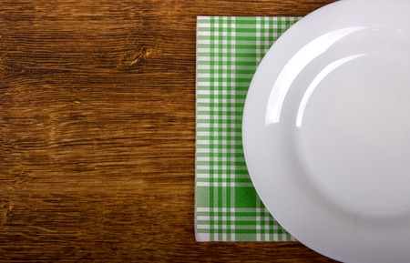 Top view of clean empty plate on wooden tabletop with napkinの写真素材