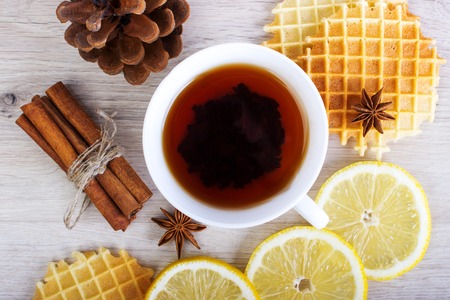 Cup of black tea with Christmas decor, lemon, pinecone, waffles, badian and cinnamon.の写真素材