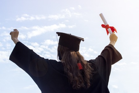 Graduate put her hands up and celebrating with certificate in her hand and feeling so happiness in Commencement day. Toned.の写真素材