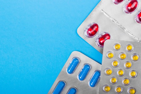 Colored pills, tablets and capsules on a blue background. Medicine and health.