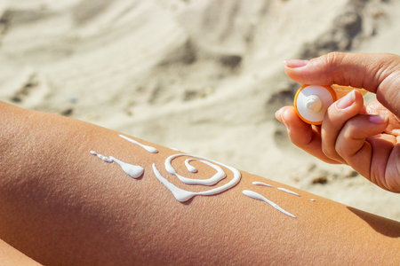 A girl smears her leg with sunscreen. Legs protected from strong sunの写真素材