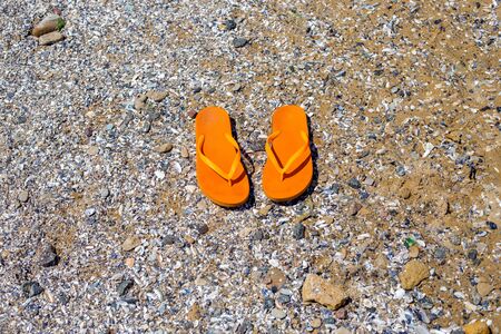 travel background with a pair of orange flip-flops in the sandの写真素材